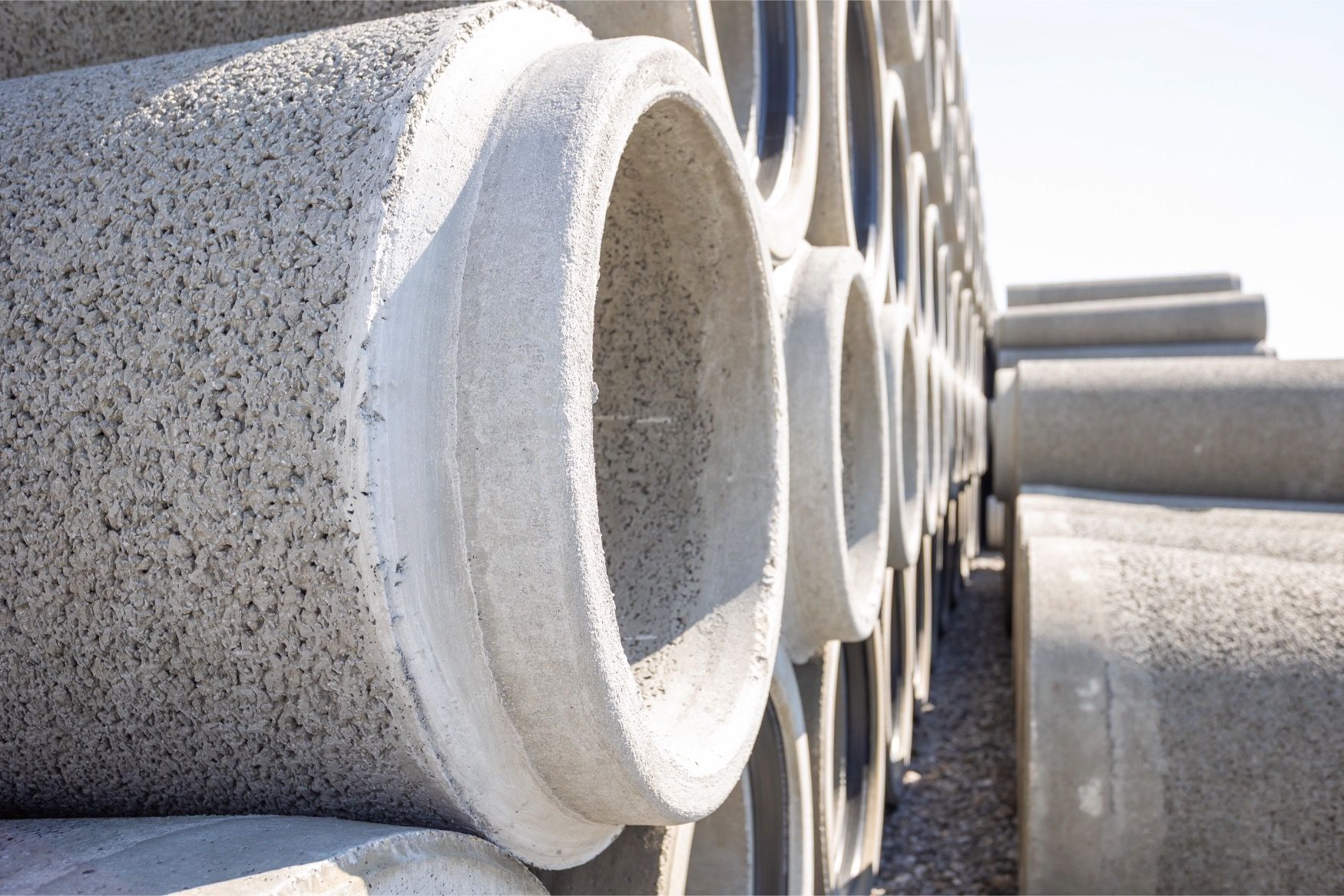 Tuyaux en béton préfabriqué empilés chez Webeco, prêts à être utilisés dans des projets d’infrastructures hydrauliques durables.