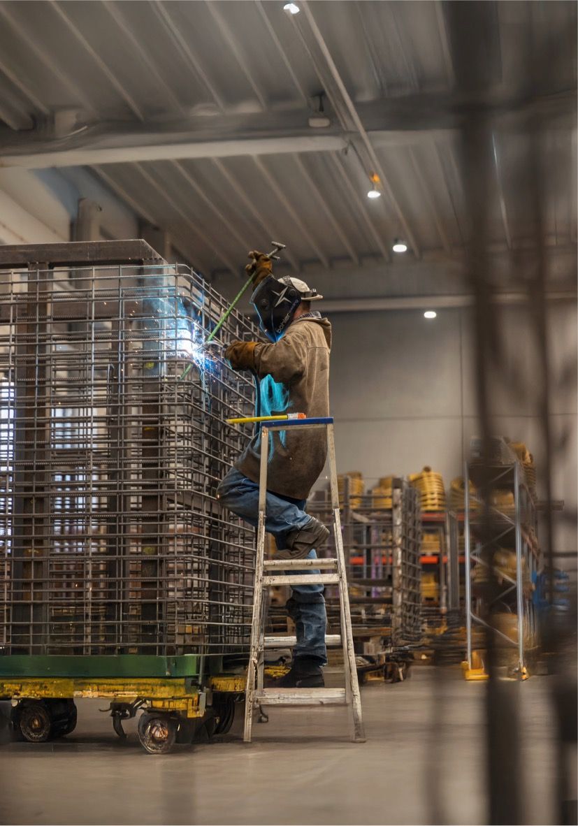 Webeco-medewerker giet beton in een mal tijdens het productieproces van prefab betonelementen in een moderne fabriekshal.